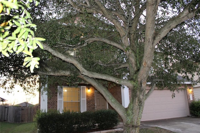 view of front of house with brick siding, fence, driveway, and a garage