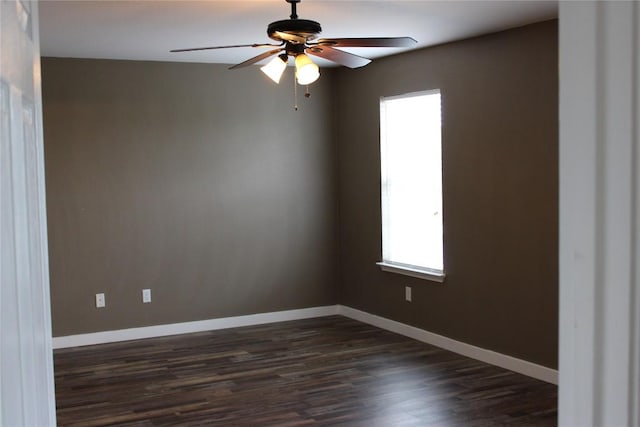 spare room featuring plenty of natural light, dark wood-style flooring, a ceiling fan, and baseboards