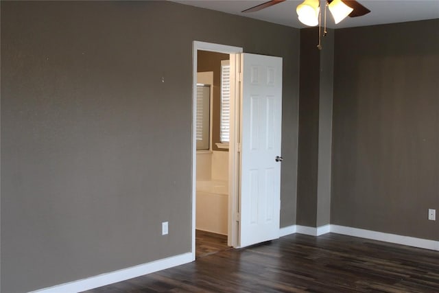 spare room with ceiling fan, dark wood-type flooring, and baseboards