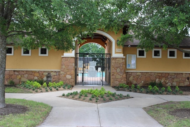 18354 Basket Flower Bnd, Elgin, TX 78621 - view of exterior entry featuring stone siding, a gate, and stucco siding