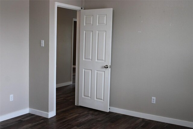 unfurnished room with baseboards and dark wood-style floors