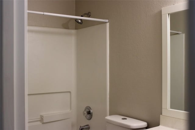 full bath with toilet, shower / tub combination, and a textured wall