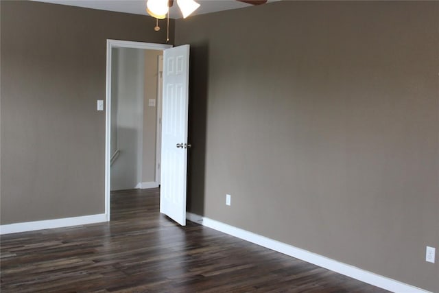 empty room with a ceiling fan, dark wood finished floors, and baseboards