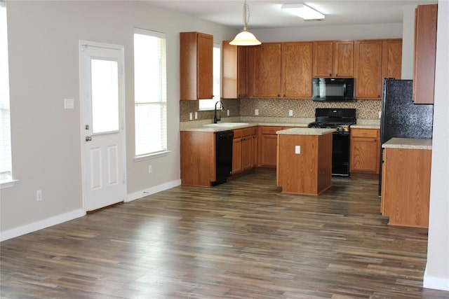 kitchen featuring black appliances, a sink, decorative backsplash, a kitchen island, and dark wood-style flooring