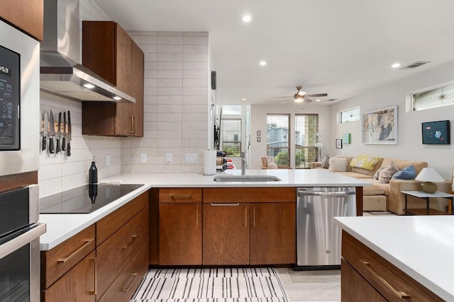 5202 Rob Scott St, Austin, TX 78721 - kitchen with wall chimney range hood, appliances with stainless steel finishes, tasteful backsplash, light countertops, and open floor plan