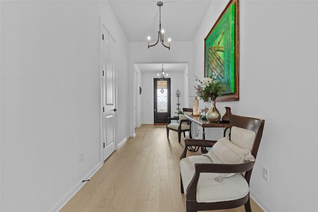 foyer with a chandelier, light wood-style floors, and baseboards