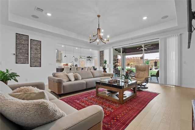 living area featuring a tray ceiling, a chandelier, wood-type flooring, and recessed lighting