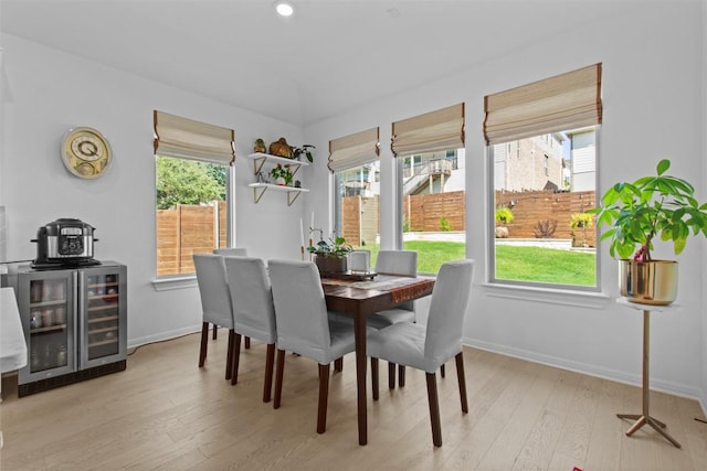 dining area featuring healthy amount of natural light, light wood-type flooring, wine cooler, and baseboards