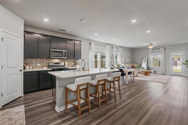 503 Windy Reed Rd, Hutto, TX 78634 - kitchen featuring stainless steel appliances, open floor plan, dark wood-type flooring, backsplash, and light countertops