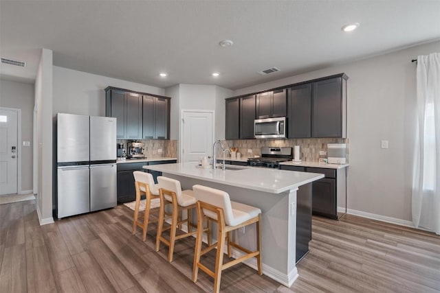 503 Windy Reed Rd, Hutto, TX 78634 - kitchen with appliances with stainless steel finishes, a sink, light wood-style floors, baseboards, and tasteful backsplash