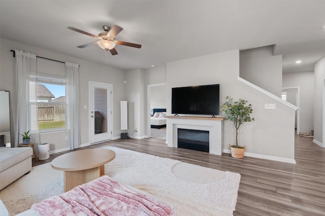 503 Windy Reed Rd, Hutto, TX 78634 - living area featuring wood finished floors, a ceiling fan, baseboards, a glass covered fireplace, and recessed lighting