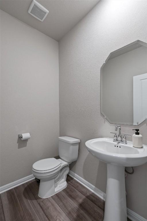 503 Windy Reed Rd, Hutto, TX 78634 - half bathroom with toilet, wood finished floors, baseboards, and a sink
