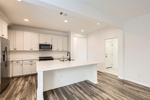 552 Windom Way, Georgetown, TX 78626 - kitchen with appliances with stainless steel finishes, a sink, dark wood-style flooring, backsplash, and a kitchen island with sink
