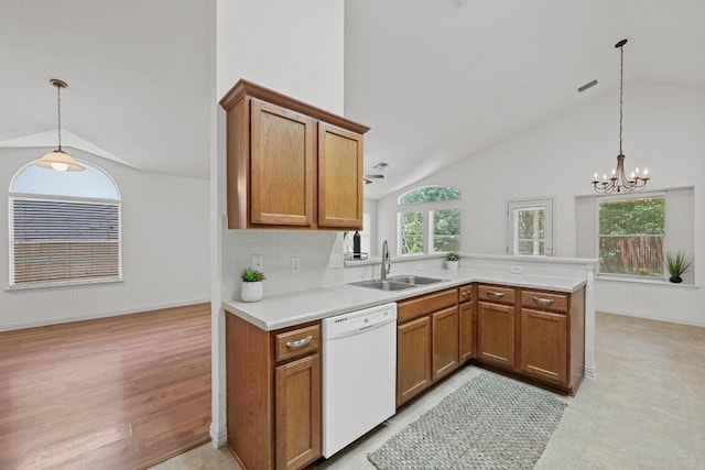 kitchen featuring dishwasher, a sink, a peninsula, brown cabinets, and light countertops