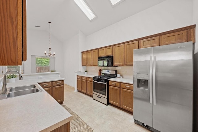 kitchen with stainless steel appliances, a sink, brown cabinets, high vaulted ceiling, and a chandelier