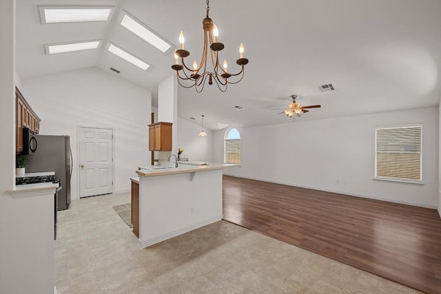 kitchen featuring black microwave, light countertops, open floor plan, a breakfast bar area, and a chandelier