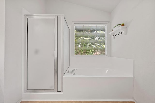 bathroom featuring a shower stall, a bath, and lofted ceiling