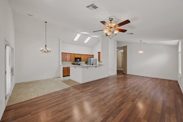 unfurnished living room featuring a ceiling fan, light wood finished floors, a chandelier, high vaulted ceiling, and a skylight