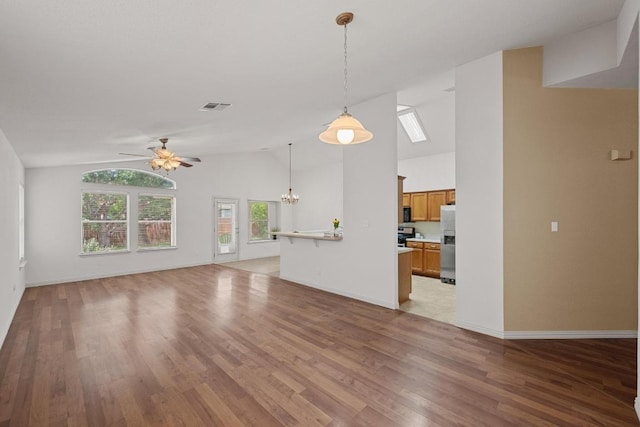 unfurnished living room with vaulted ceiling, a chandelier, ceiling fan, light wood-style floors, and baseboards