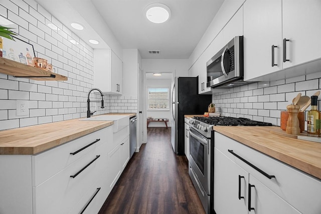 5916 Signal Pt, Austin, TX 78724 - kitchen with stainless steel appliances, wooden counters, backsplash, dark wood-style floors, and white cabinets