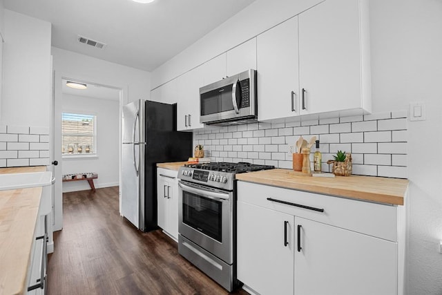 5916 Signal Pt, Austin, TX 78724 - kitchen featuring appliances with stainless steel finishes, butcher block counters, dark wood-style flooring, white cabinetry, and tasteful backsplash