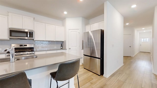 221 Mendoza, Kyle, TX 78640 - kitchen featuring stainless steel appliances, white cabinetry, light wood-style floors, recessed lighting, and backsplash
