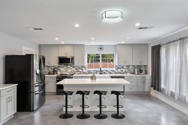 361 Whispering Hollow Dr, Kyle, TX 78640 - kitchen featuring appliances with stainless steel finishes, concrete flooring, gray cabinetry, decorative backsplash, and recessed lighting