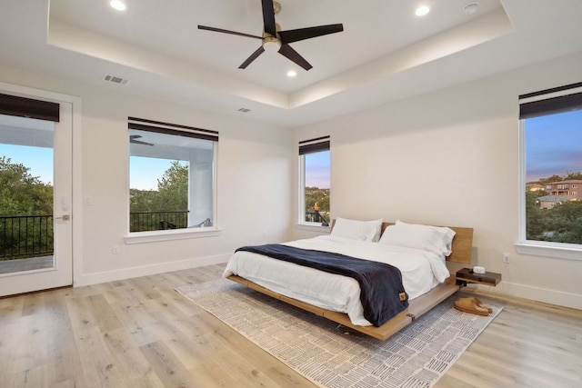 20704 Leaning Oak Dr, Lago Vista, TX 78645 - bedroom with a raised ceiling, access to outside, light wood-type flooring, multiple windows, and recessed lighting