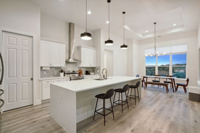 20704 Leaning Oak Dr, Lago Vista, TX 78645 - kitchen featuring stainless steel electric stove, wall chimney range hood, a high ceiling, decorative backsplash, and light wood finished floors