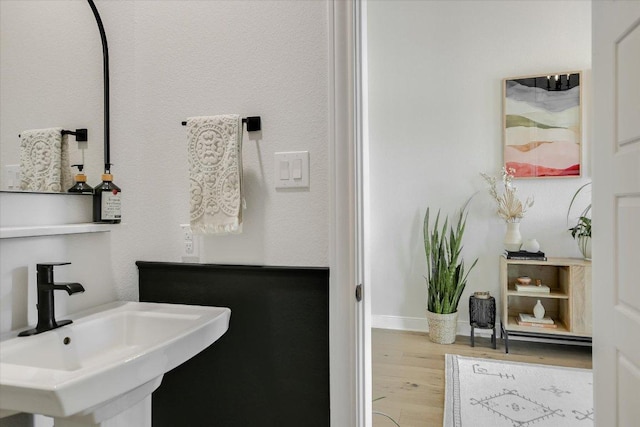 bathroom with a sink, wood finished floors, and baseboards