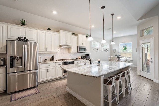 512 Bell Boot Pass, Georgetown, TX 78626 - kitchen featuring appliances with stainless steel finishes, light wood-style flooring, white cabinetry, light stone counters, and recessed lighting