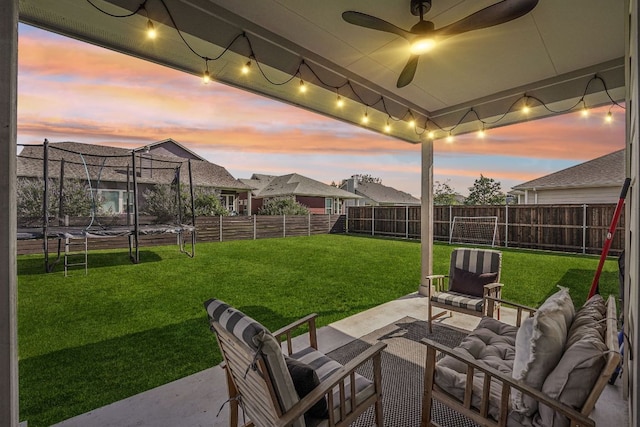 patio terrace at dusk featuring a trampoline, an outdoor hangout area, and ceiling fan