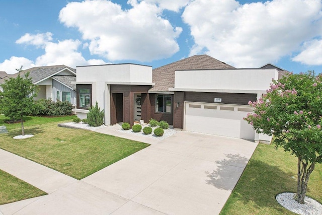 contemporary home featuring a garage, driveway, a front yard, and stucco siding