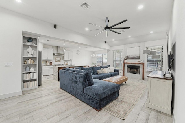 living area with ceiling fan, light wood-type flooring, a fireplace, recessed lighting, and baseboards