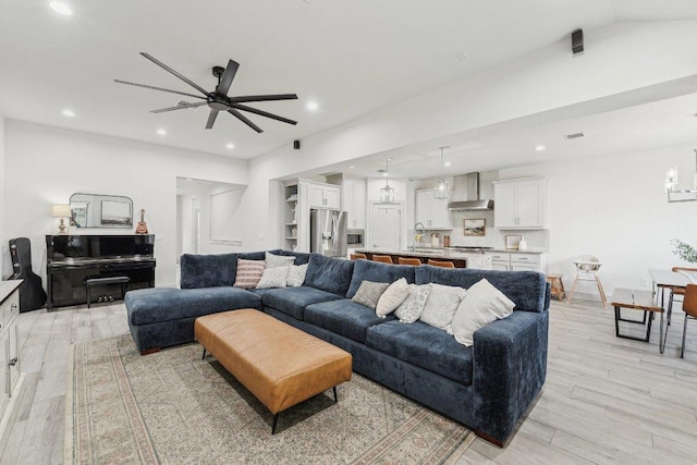 living room with ceiling fan, light wood-style flooring, recessed lighting, and a chandelier