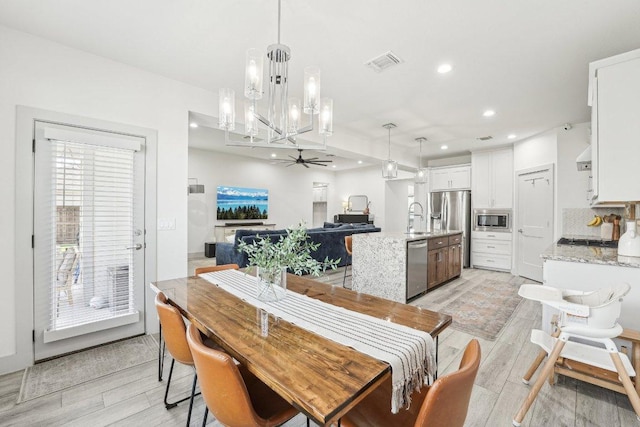 dining space with ceiling fan, light wood-type flooring, recessed lighting, and a chandelier