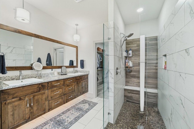 full bathroom with a walk in shower, double vanity, tile patterned flooring, and a spacious closet