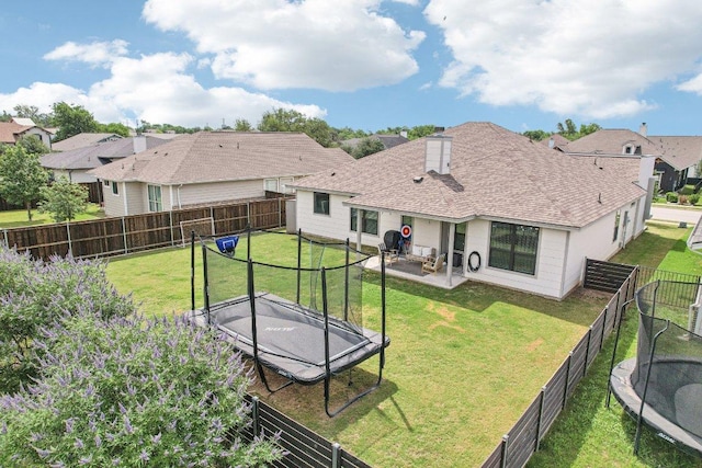 rear view of property with a trampoline, a patio area, roof with shingles, and a residential view
