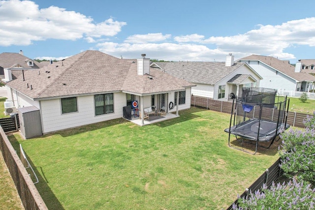 back of property featuring a trampoline, a patio, a shingled roof, and a chimney