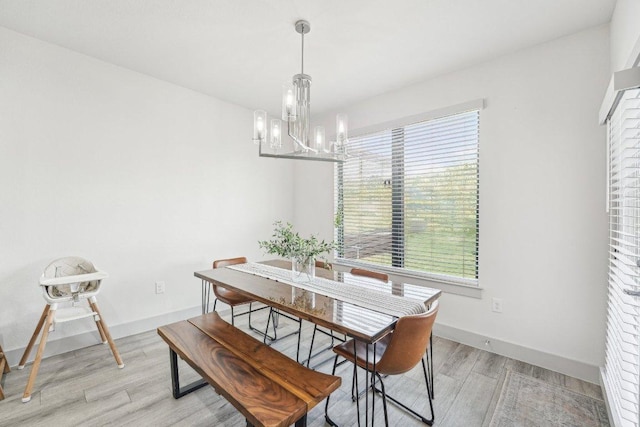 dining room featuring a chandelier, light wood-style floors, and baseboards