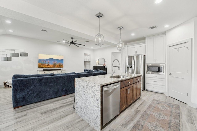 kitchen featuring appliances with stainless steel finishes, a sink, light stone counters, recessed lighting, and white cabinets