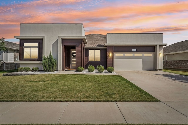 modern home featuring driveway, an attached garage, a front lawn, and stucco siding