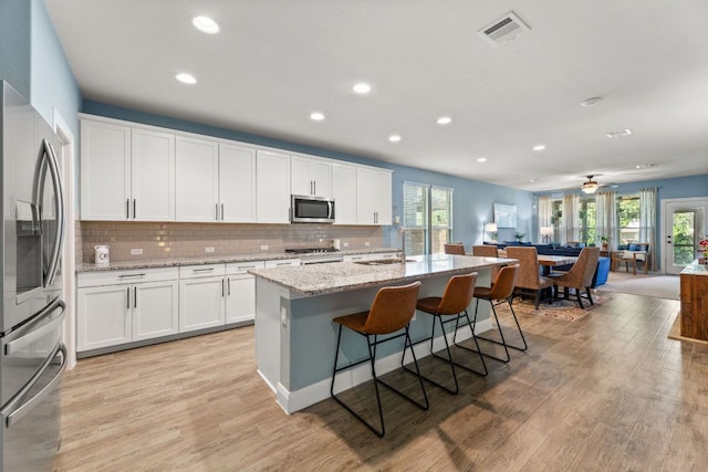 kitchen with appliances with stainless steel finishes, healthy amount of natural light, open floor plan, recessed lighting, and decorative backsplash