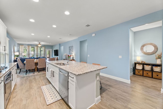 kitchen with a sink, stainless steel appliances, white cabinets, light wood-style floors, and recessed lighting