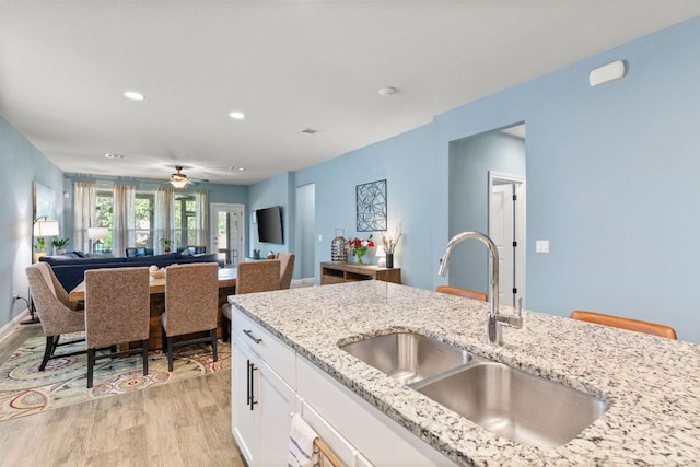 kitchen featuring a sink, light wood-type flooring, white cabinetry, open floor plan, and recessed lighting
