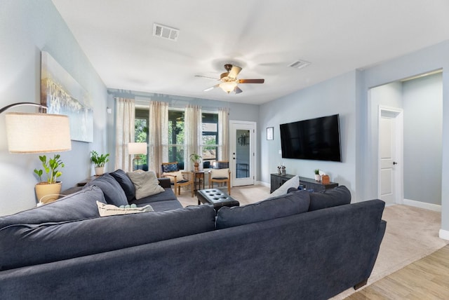 living room with baseboards, a ceiling fan, and light wood-style floors