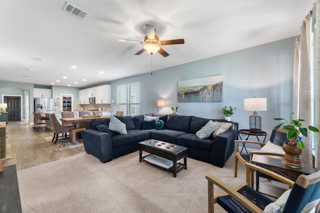 living room with a ceiling fan, light wood finished floors, arched walkways, and recessed lighting