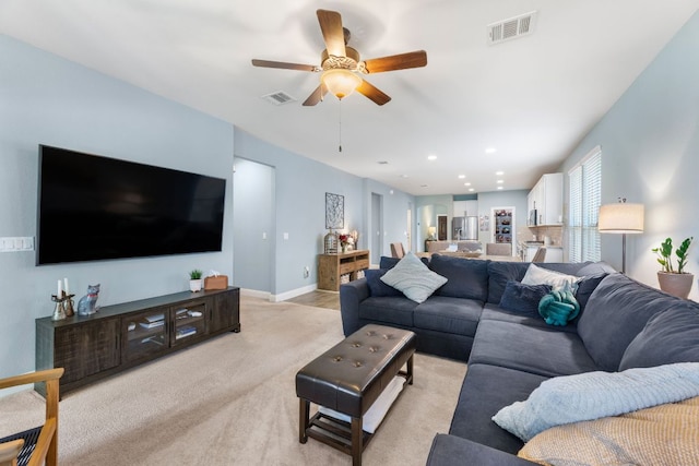 living room with ceiling fan, light colored carpet, and baseboards