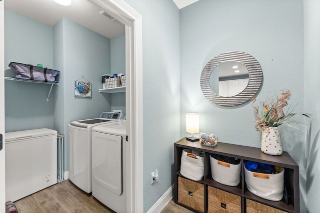clothes washing area with light wood-style floors, washing machine and clothes dryer, and baseboards