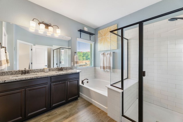 bathroom with a stall shower, a garden tub, wood finished floors, and double vanity